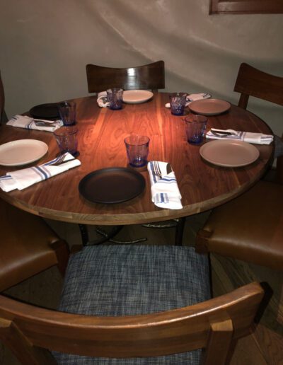 A wooden dining table with four chairs and a place setting.