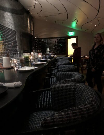 A woman is standing in front of a bar in a restaurant.