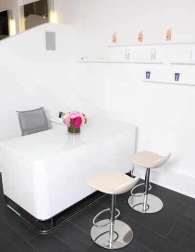 An office with a white desk and two stools.