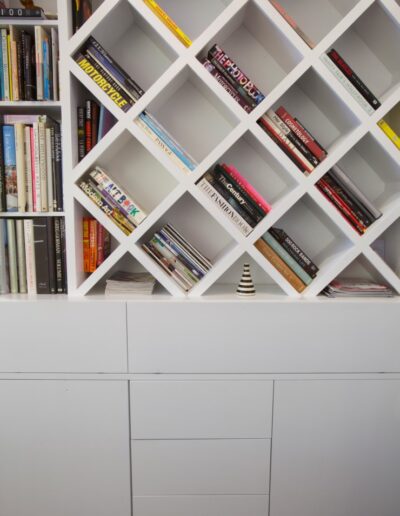 A white bookcase with a lot of books on it.