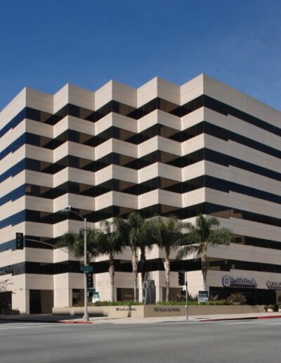 A large building on a corner with palm trees.