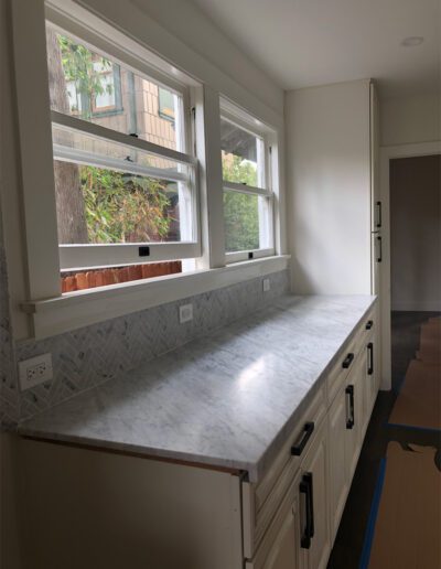 A kitchen with a marble counter top and a window.