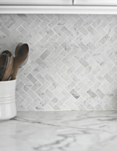 A kitchen with a marble backsplash and utensils.