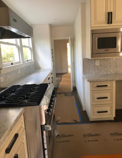 A kitchen is being remodeled with white cabinets and a stove.