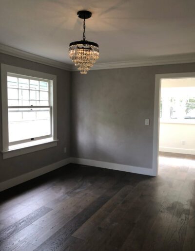 An empty room with gray walls and hardwood floors.