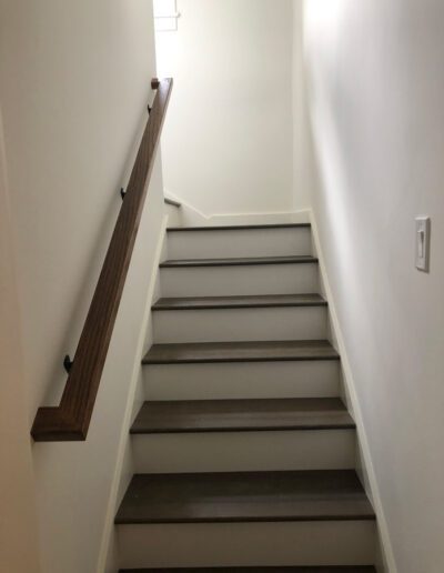 A white staircase with a wooden handrail.