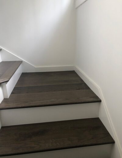 A staircase with wood floors and white walls.