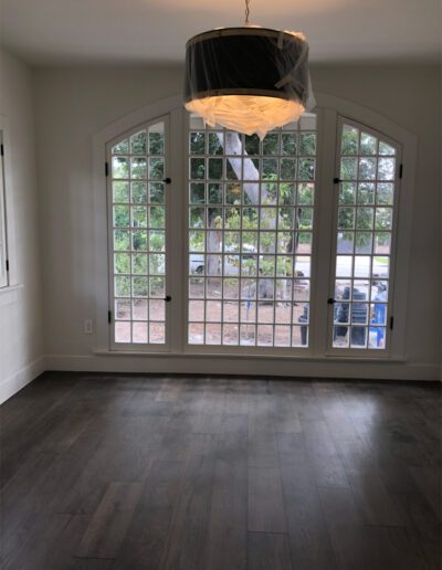 An empty room with hardwood floors and a chandelier.