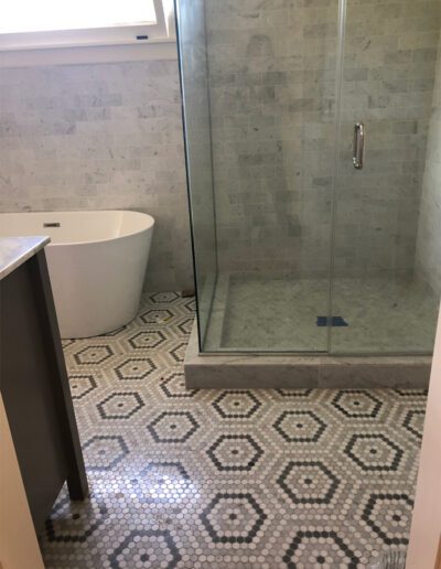 A bathroom with a tiled floor and a shower stall.