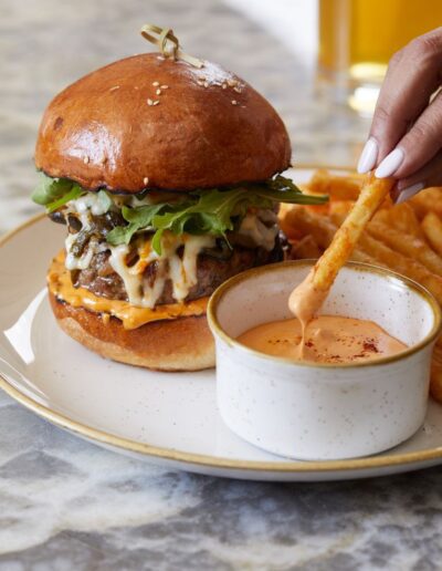 A person is dipping french fries into a bowl of ketchup.