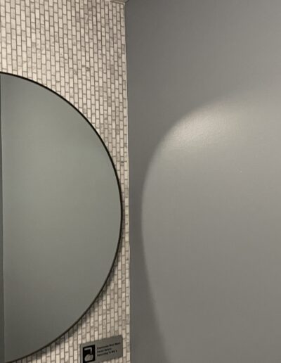 A woman is standing in front of a mirror in a bathroom.