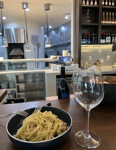 A plate of pasta and a glass of wine on a table.