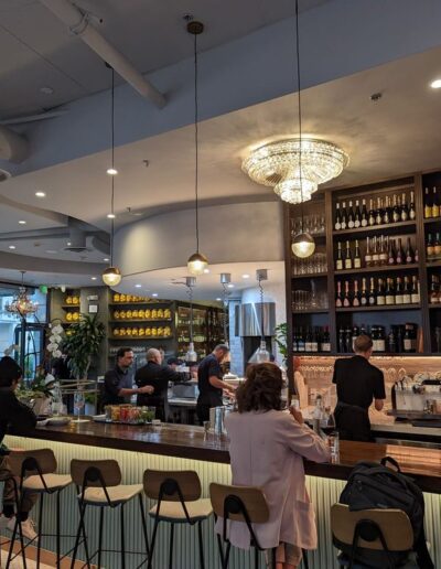 The interior of a restaurant with people sitting at the bar.