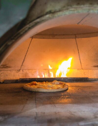 A pizza is being cooked in a wood fired oven.