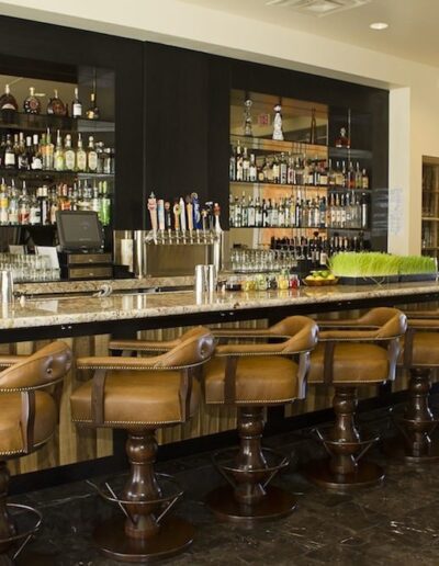 A bar with several stools and a bottle of liquor.